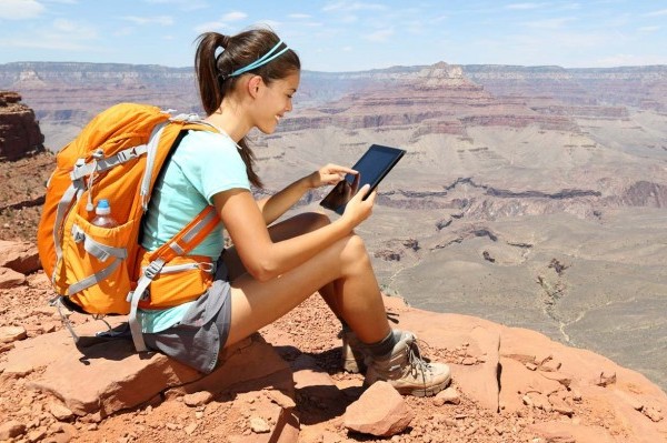 student sitting on mountain using tablet
