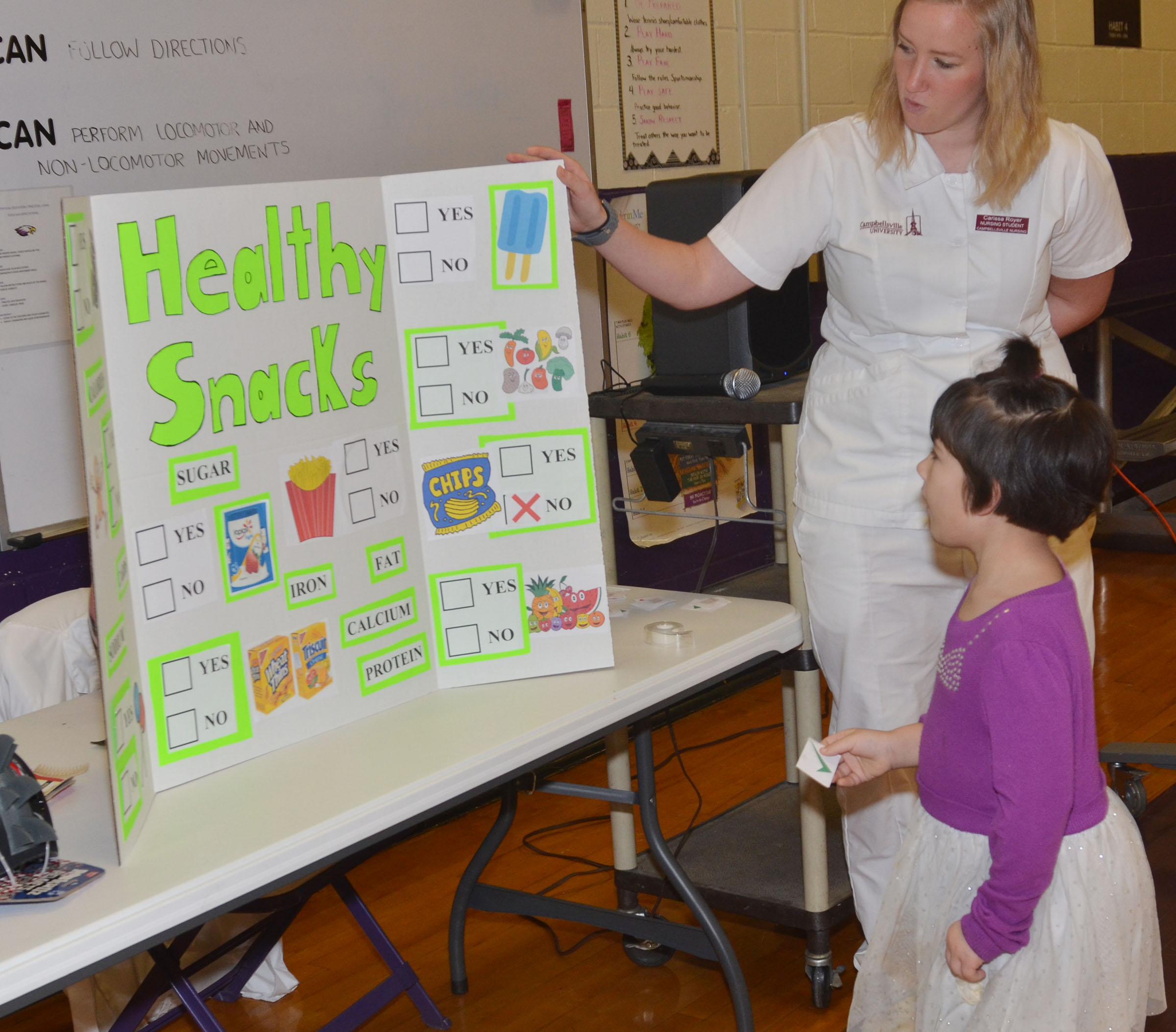 CU nursing student Carissa Royer asks CES kindergartener Madison Nunn to choose a healthy snack.