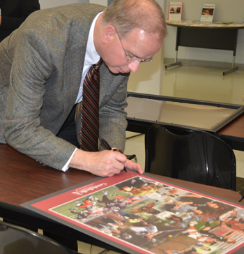 Dr. Michael V. Carter, president of Campbellsville University, signs one of the new Campbellsville University academic/athletic posters for U.S.  Congressman Ed Whitfield.  (Campbellsville University Photo by Joan C. McKinney)