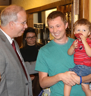 Dr. Michael V. Carter, left, talks with Josh  Houk, a 2008 graduate, at the Owensboro  event. Houk is holding his son, Josiah.  (Campbellsville  University Photo by Drew  Tucker)