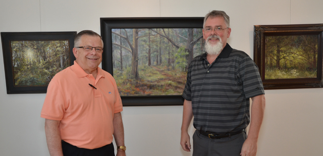 Dr. John Chowning, left, talks with Bill Guffey, an artist from Cumberland County, which is  Chowning's native home. They were discussing the middle painting, Chowning's favorite. The art work will be on display at the Pence-Chowning Art Gallery, 205 University Drive, through  Sept. 12. The Pence-Chowning Art Gallery is named after Chowning, vice president for church  and external relations andexecutive assistant to the president at Campbellsville University,  and his wife, Cathy Pence Chowning. (Campbellsville University Photo by Joan C.  McKinney)