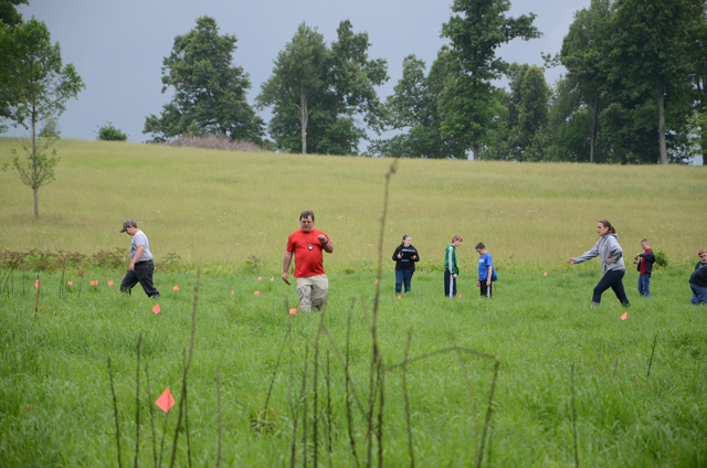 Tromping through new grass on a May morning was favored by most of these students from Lebanon Middle and Campbellsville Independent schools over sitting in a classroom. Kentucky Archaeological Survey staff archaeologist Eric Schlarb, facing the camera, was the lead archaeologist of three to visit Clay Hill Memorial Forest and survey for historic artifacts. (Campbellsville University Photo by Linda Waggener)