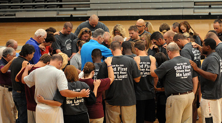  Ed Pavy, Campbellsville University's campus minister, in blue shirt, leads the commissioning prayer during a send off at CU's Powell Athletic Center for the seven-day Costa Rica mission trip. (Campbellsville University Photo by Richard RoBards)