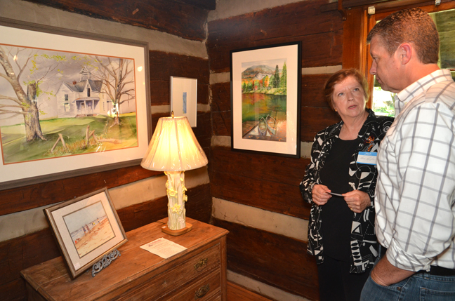 Cora Renfro, right, an artist from Columbia, Ky., discusses her work, which includes the lamp, to Chris Reynolds of Campbellsville, at Campbellsville University's Log Cabin Art Shop which opens to the public Sept. 4. (Campbellsville University Photo by Joan C. McKinney)