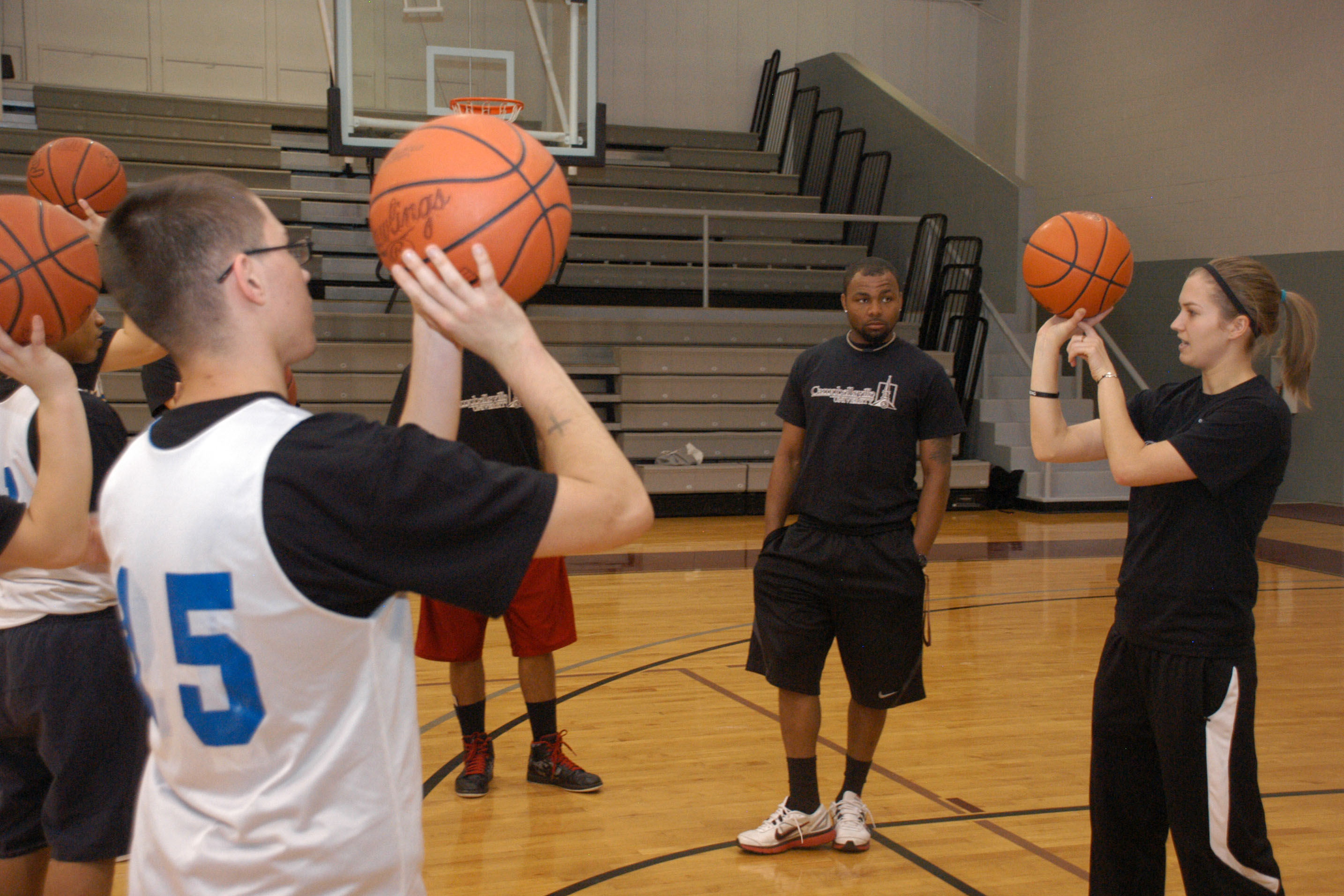 Campbellsville University Lady Tiger basketball senior Courtney Danis of Mt. Sterling, Ky., helps teach basketball with the boys from Lincoln Village. Jeffery Demary, a cornerback with the CU football team from Columbia, S.C., assists Danis. (Campbellsville University Photo by Chris Megginson)