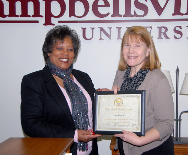 Greater Campbellsville United recently gave its Outstanding Service Award to Lynn Ann Rausch, information center attendant at Campbellsville University. The award, presented by GCU Director Wanda Washington at left, stated that Rausch “has the most pleasant voice behind the phone and provides outstanding service to all people.” Washington told attendees at the GCU meeting where the announcement was made that she had talked with relatives to discover more about the award winner who always gives kind and thorough service to all callers. She said that Rausch is known to have a “gentle, humble disposition, and is thought of as a wonderful wife, sister, mother and grandma.” Washington also discovered that Rausch has “a beautiful singing voice, paints like a pro and cooks better than any cooking channel chef.” The GCU award is given for service that is above and beyond. (Campbellsville University Photo by Linda Waggener)