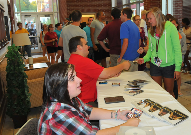 Kira Stewart, right, a freshman from St. Louis, picks up her trading card from Jessica Porche and Paul Bray at Ransdell Chapel. (Campbellsville University Photo by Joan C. McKinney)