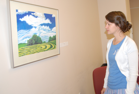 Megan Dudley of Greensburg, a tutor in the Learning Commons, views one of the  art exhibit offerings by Linda J. Cundiff. (Campbellsville University Photo by Nicholas Osaigbovo)