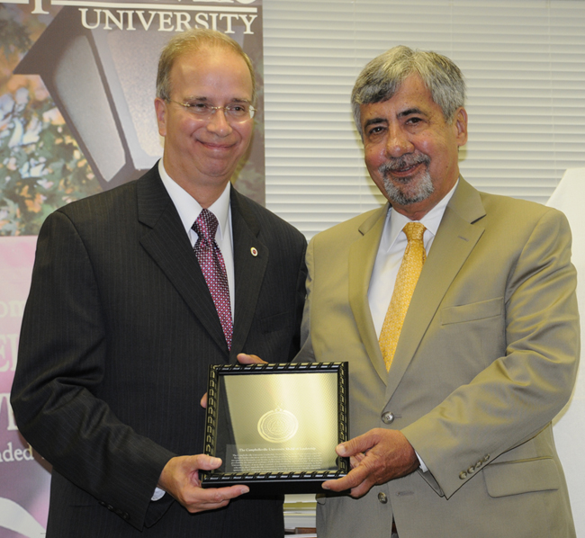 Guy Montgomery, right, Campbellsville University Trustee, was given three awards at CU Louisville’s commencement convocation June 11 to honor his family’s legacy of support. President Michael V. Carter, left, presented the Library Recognition plaque (a small version of the one which will hang in the library) for his help in growing the CU-Louisville Mongtomery Library. He also received the CU Leadership Award and a newly-created award, the Montgomery Superstar sports card. (Campbellsville University Photo by Linda Waggener)