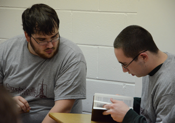 Andrew McGinnis, a CU senior from Danville, Ky.,   helps Atkins, a teen from Lincoln Village, find   a passage of scripture. (Campbellsville University   Photo by Christina L. Kern)