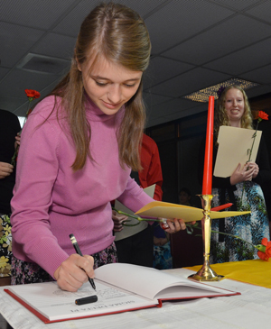 Sarah Theimer, a senior of Beavercreek, Ohio, signs in as she is initiated into the Omega Mu chapter of Sigma Delta Pi Spanish honor society at CU. (CU Photo by Gerry James)