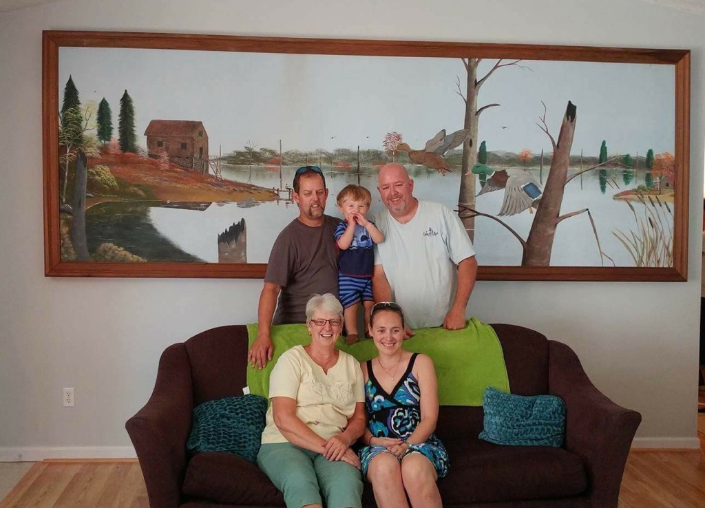 Seated in Myna Graham’s home, with the painting her husband painted now in their home. From left are: Front row -- Myna Graham; Victoria Graham, Jerry’s daughter-in-law, married to Michael. Back row: Michael Graham, Jerry’s son; Lucas Graham, Michael’s son; and Jerry Keith Graham, Jerry’s oldest son. Keith lives in Nicholasville, Ky., and made preps for the installation and helped put the painting in their house. (Campbellsville University Photo by Jesse Harp)