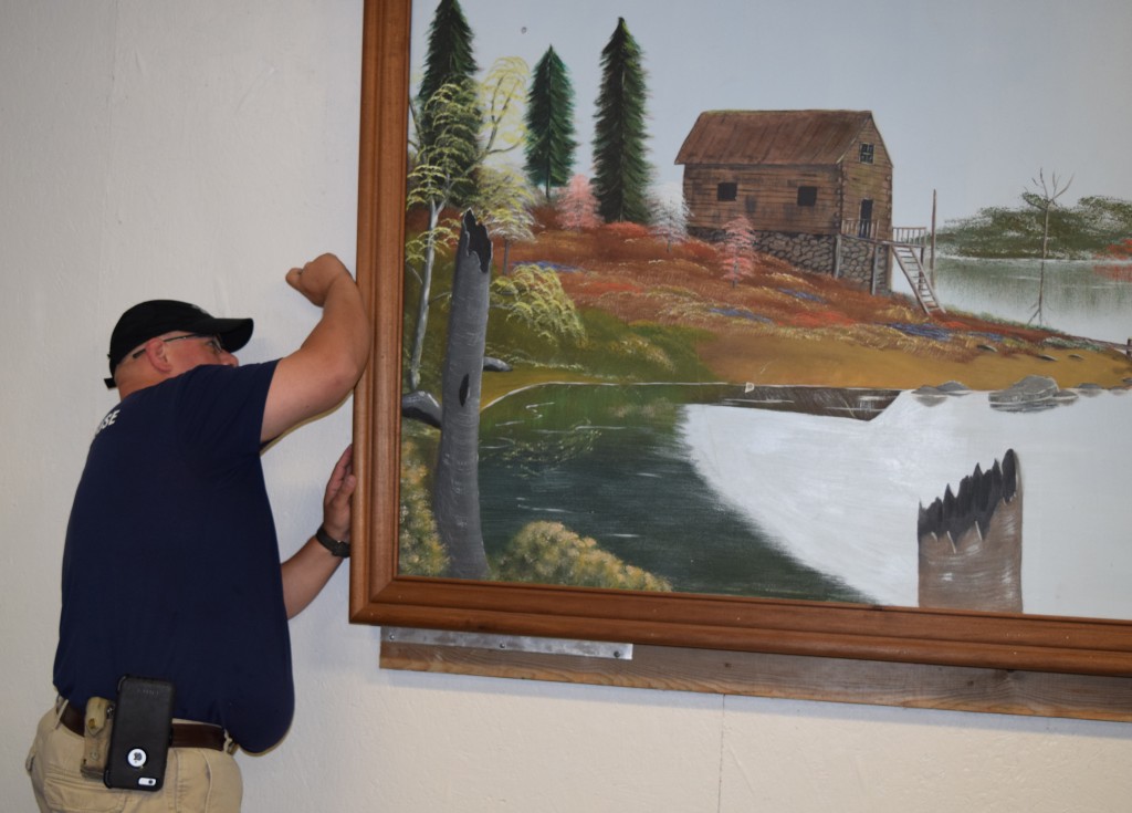 Damon Graham, son of Myna Graham and the late Jerry Graham, takes down the painting his father painted and that hung in Campbellsville University’s Physical Plant for several years. (Campbellsville University Photo by Jesse Harp)
