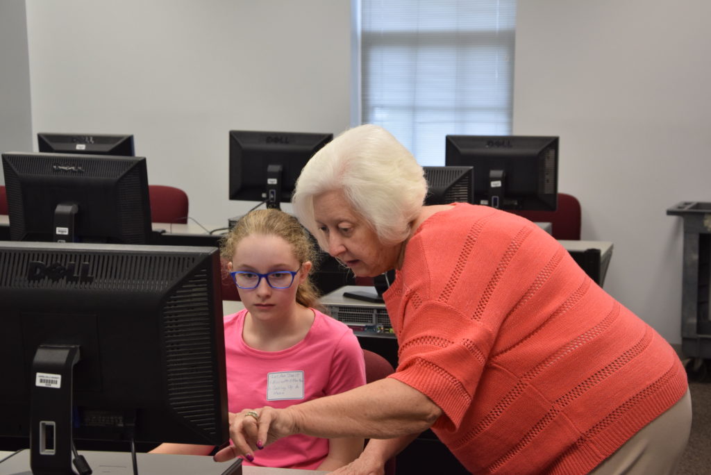 From left, LeeAnna Darst of Acton, Ky., gets instruction from Pat Hall in the Microsoft Office class offered during Kids College, a program that took place on Campbellsville University’s campus. (Campbellsville University Photo by Ariel Emberton)