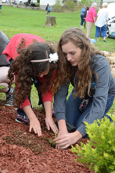 Raven Johnson, on right, helps a student from Kentucky Christian Academy to plant a sapling during the Earth Day ceremony at Campbellsville University. (Campbellsville University Photo by Tomomi Sato) 