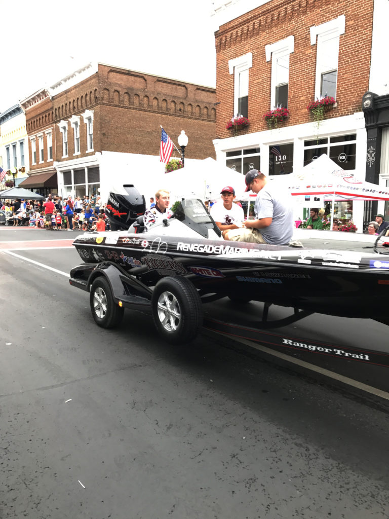 Campbellsville University’s bass fishing team was represented in the parade by, from left: Justin Mayfield of Somerset, Ky., and incoming freshmen Ezra Oliver of Campbellsville and Tanner Barnes of Campbellsville, step-son of Megan Barnes, coordinator of introductory studies early alert system at the university. Pulling the boat were team members Colby Hays of Somerset and Travis Hunt of Campbellsville. (Campbellsville University Photo by Joan C. McKinney)