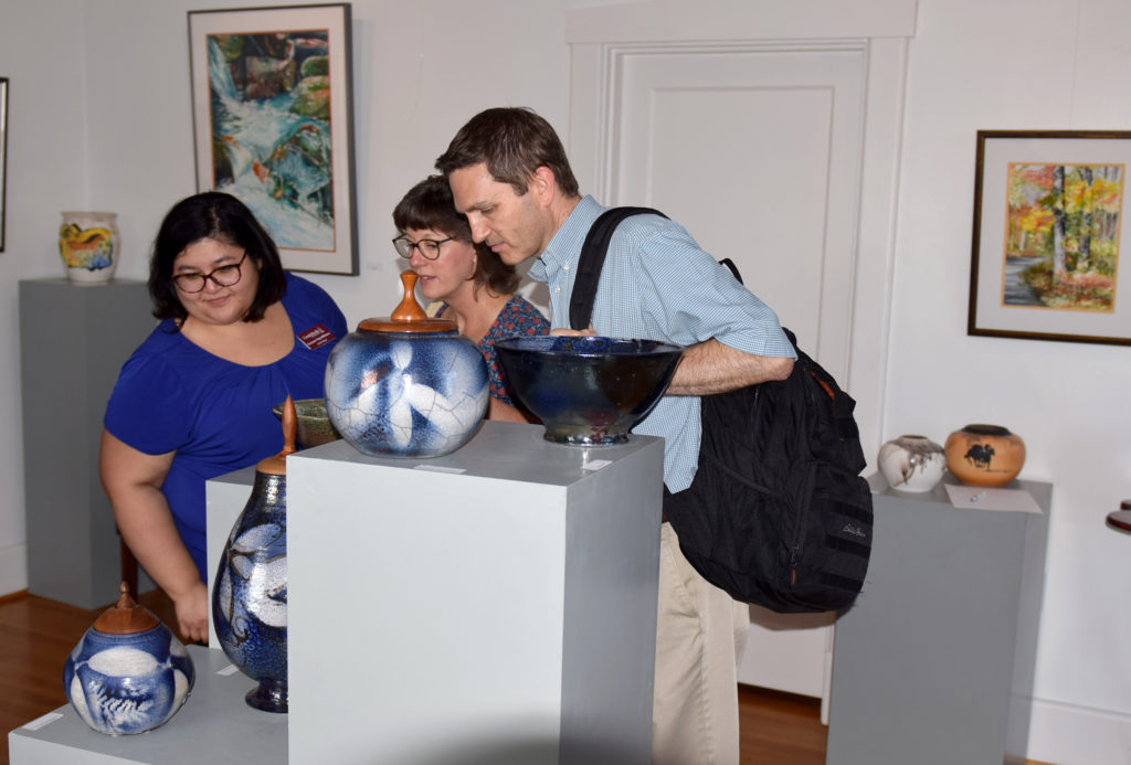 Susie Trejo Williams, left, assistant professor of art and design at Campbellsville, shows some of the Scott’s art to Vonnie and Stephen Skaggs at the reception honoring the Scott’s work. (Campbellsville University Photo by Luke Young)